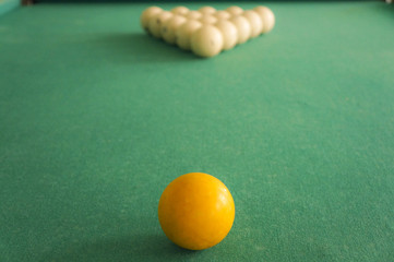 Russian billiards - large white balls with an orange cue and a wooden cue on a large table with green cloth