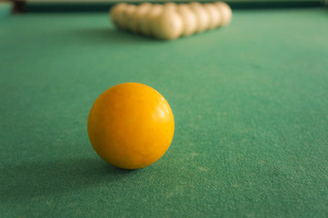 Russian billiards - large white balls with an orange cue and a wooden cue on a large table with green cloth