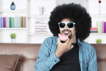 Funny person eats donuts on couch