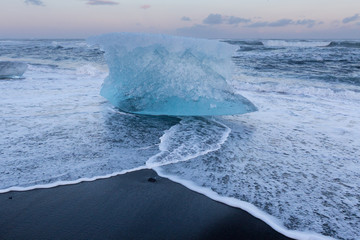 Glacial Ice breaking on black sand beach, Iceland winter natural landscape background