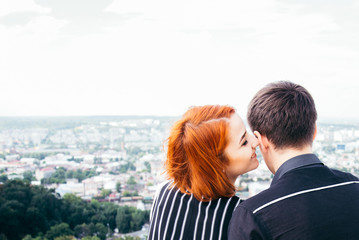 young woman sits with her boyfriend on the peak of the hill