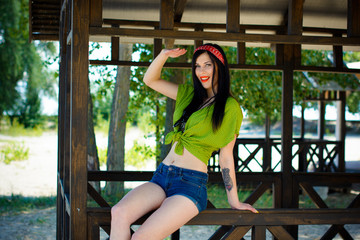 Pretty brunette woman in pin up style have fun and enjoying life on vacation. Stylish inspire vintage lady on a beach near wooden alcove, water and sand