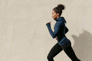 Side view of female athlete running outdoors, cropped shot