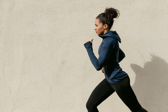 Fototapeta Side view of female athlete running outdoors, cropped shot