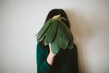 Girl holding plant in front of face