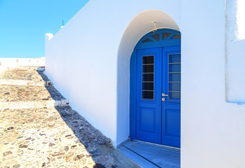 Bright blue doors, shutters and perfect white washed walls in the back streets of fira, Santorini, Greece.