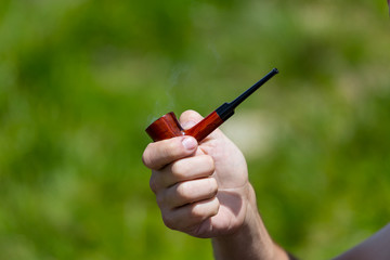 closeup tobacco pipe in a man fingers