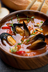 Close-up of a wooden bowl with mussels soup, selective focus, shallow depth of field