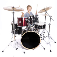 Fototapeta na wymiar young caucasian boy plays drums in studio against white background