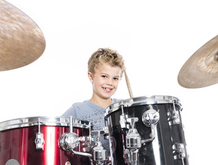 young caucasian boy plays drums in studio against white background