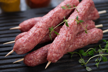 Close-up of fresh uncooked cevapcici or balkan skinless beef sausages on skewers, selective focus, shallow depth of field