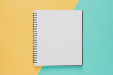Office workplace minimal concept. Blank notebook on yellow and blue background.