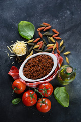 Bolognese sauce with penne pasta and other italian cooking ingredients, top view, vertical shot