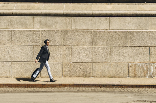 Latino Businessman on the move in the city with suitcase 