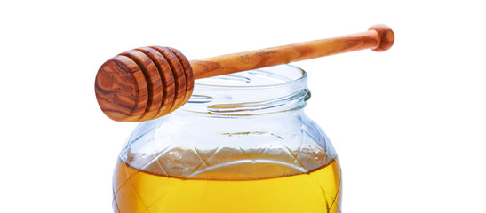 Glass jar full of honey wooden dipper