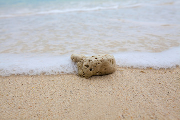 Abstract background of coral on sandy beach with soft waves and beach waves.