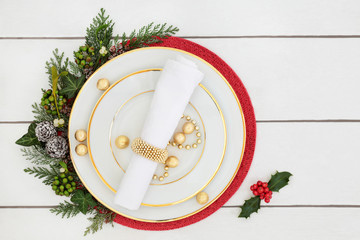 Christmas dinner table setting with porcelain plates, napkin, decorations and gold foil wrapped...