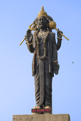 High statue of the Indian deity Shani with raised hand. Monument to the planet's Saturn lord, the most impartial god in hinduism, symbol of justice