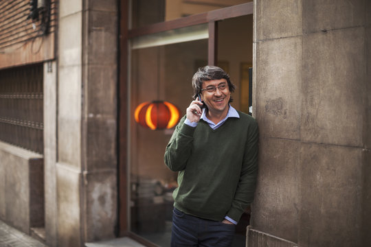 Mature interior designer man talking with smartphone in front his creative studio.