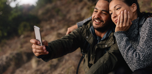 Loving young couple on hike taking a selfie - obrazy, fototapety, plakaty