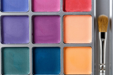 professional cosmetics. Palette of multicolored eye shadow and makeup brush, top view