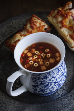A cup of Minestrone soup with mozarella and red onion focaccia bread shot with low key lighting 