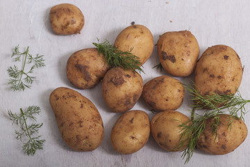 Fresh raw potatoes on a white wooden background. Top view