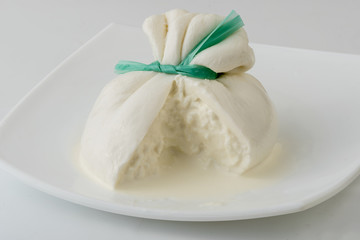 Burrata cheese isolated on white plate. Sliced fresh italian cheese made from mozzarella and cream.