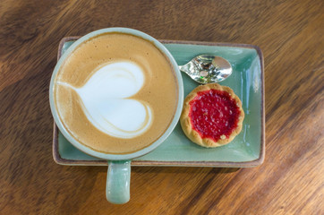 coffee cup with heart shape with strawberry biscuit on blue plate