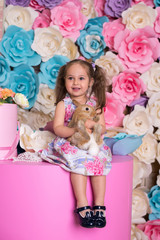 Happy laughing little girl playing with a baby rabbit, hugging her real bunny pet and learning to take care of an animal. Child on a floral background