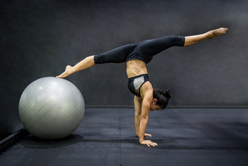 Young Asian athlete woman doing pilates exercises with exercise ball in fitness gym, healthy lifestyle concepts