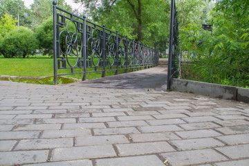 Forged bridge railing through a small river in the park. Locks on the railing, as a symbol of eternal love for the newlyweds.