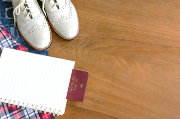 Fototapeta na wymiar travel accessories and costume on wood floor, jeans, shirt. shoes, passport. book