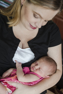 A first-time mother lovingly holds her mixed-race newborn baby girl.