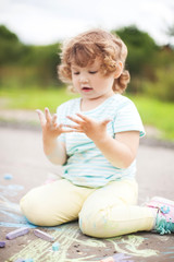 Fototapeta premium Cute toddler girl looking at her dirty hands