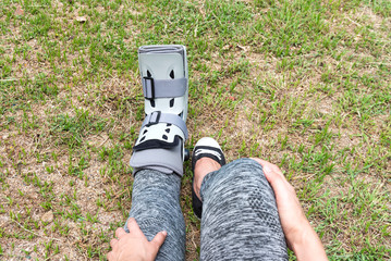 injured woman wearing sportswear  broken ankle wearing ankle support on exercise equipment in a...
