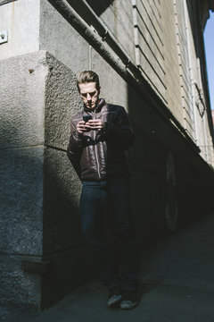 Man in the shadows sending secret messages on his smartphone