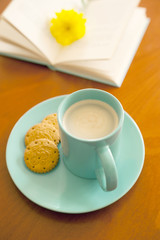 aquamarine mug of coffee with biscuits and book
