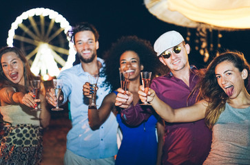 Group of young tourist friends cheering with rosè and normal champagne at beach party