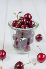 Fresh, sweet cherries in a bowl. White wooden, background.