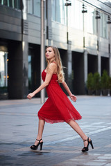 Obraz premium Beautiful blonde lady in red dress on White Square office center in Moscow, Russia