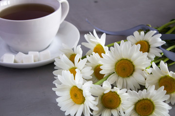 Fototapeta na wymiar White flowers and tea on the grey background