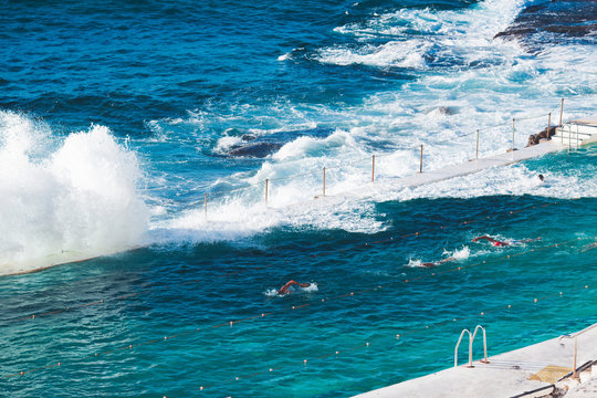 People swimming in a pool at the edge of the sea in Bondi beach