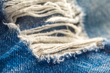 Loch mit Fäden in einer Blue Jeans in Used-Optik