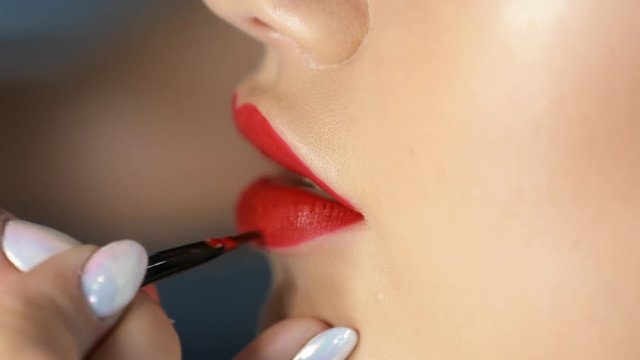 girl paint lips red lipstick in the beauty salon