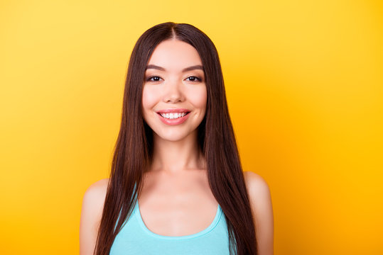 Close up portrait of young charming asian lady, standing on the yellow background and smiling, wearing casual blue singlet