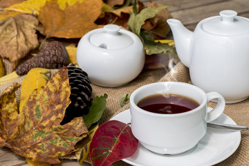 Autumn leafs with cup of tea on brown wooden table