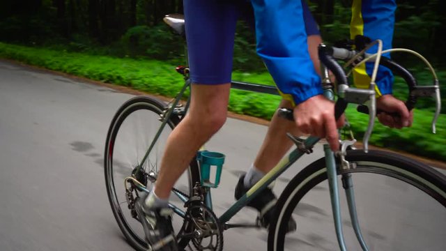 Middle-aged man is riding a road bike along a forest road
