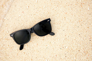 Top view of sunglasses on the beach near the blue sea. Sand and glasses. Summer vacation actually relaxing, Thailand. Close up.