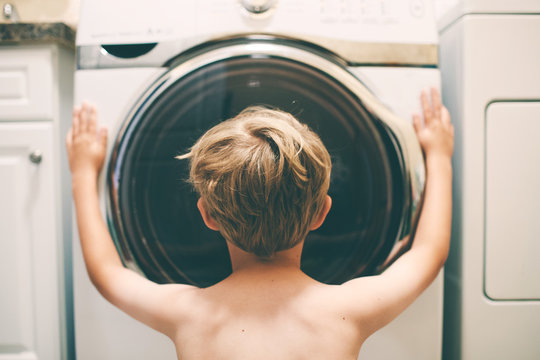 boy watches clothes spinning in a washing machine